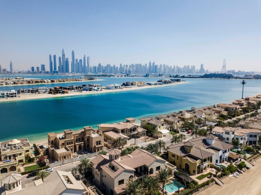Aerial view of villas and waterfront with Dubai skyline representing Jumeirah Dubai real estate