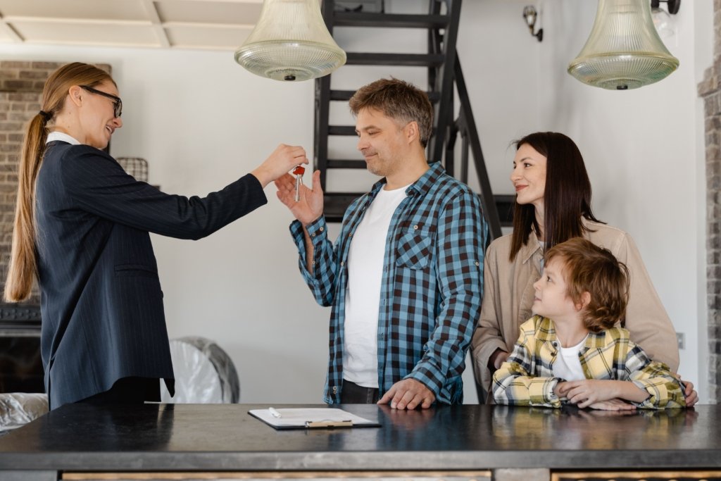 Real estate agent handing over house keys to a smiling family after completing a Dubai property sale