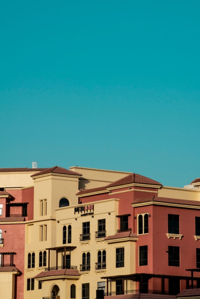 Colorful low-rise apartment buildings in Dubai Land Residence Complex under a clear blue sky