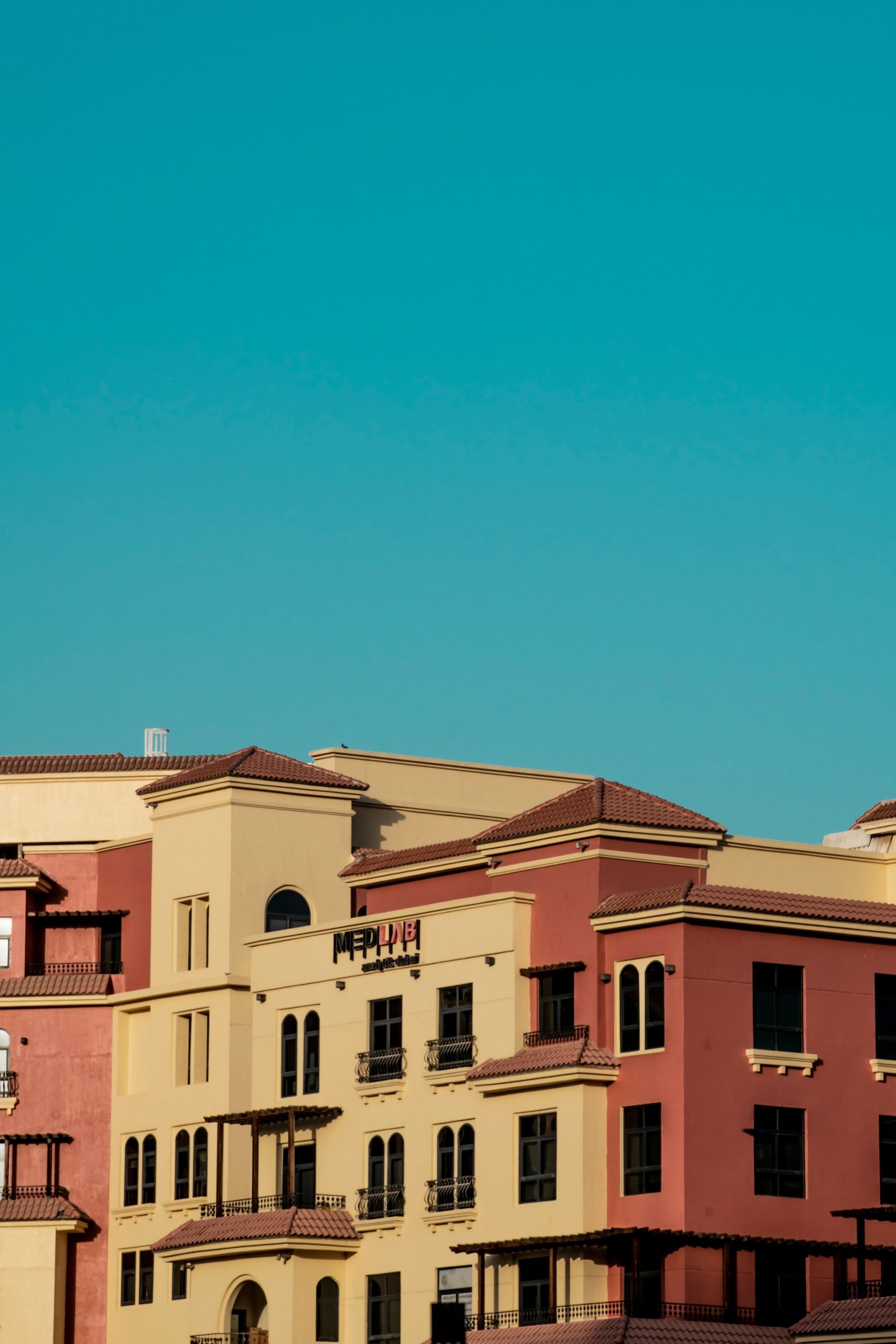 Colorful low-rise apartment buildings in Dubai Land Residence Complex under a clear blue sky