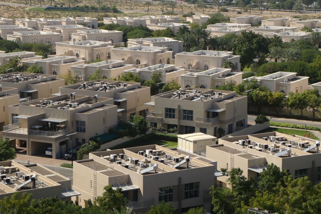 Aerial view of a Dubai residential villa community with dense low-rise rooftops and green landscaping