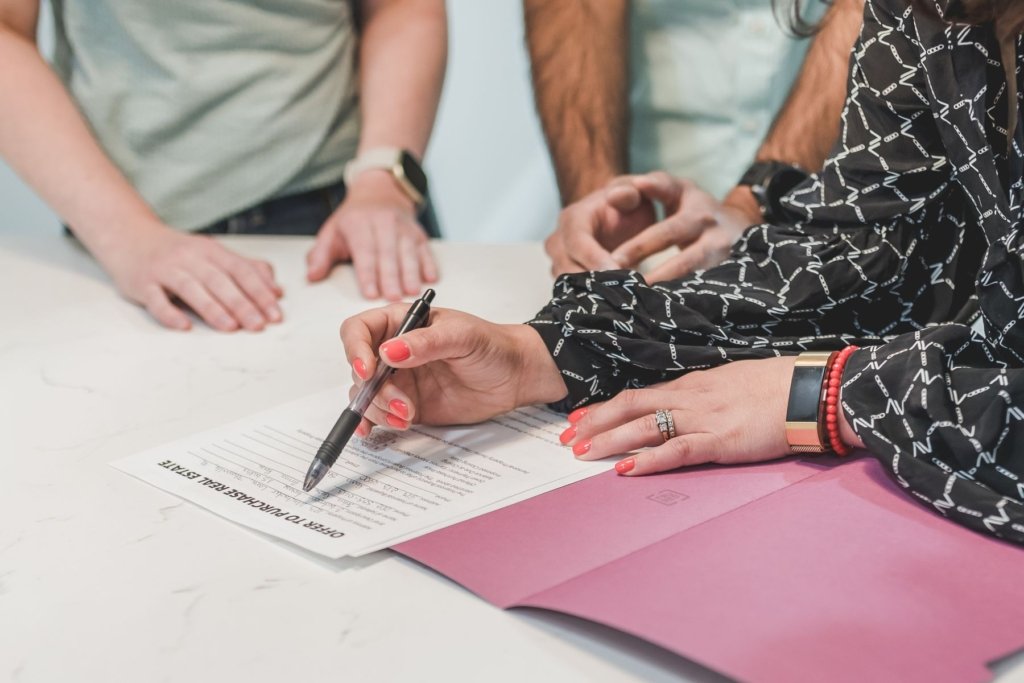 Buyers signing an offer to purchase real estate document with a pen