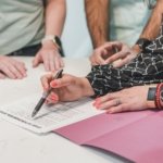 Buyers signing an offer to purchase real estate document with a pen