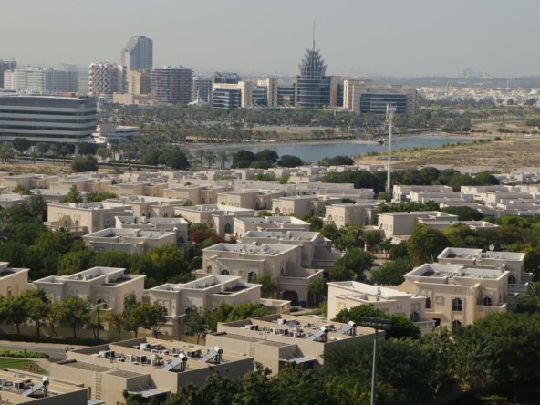 Aerial view of an established Dubai residential villa community with palm-lined streets, representing affordable freehold areas under AED 2 million