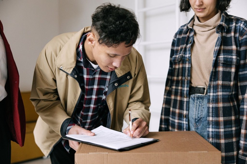 Tenant signing tenancy contract paperwork next to a moving box while relocating into a Dubai rental unit
