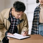Tenant signing tenancy contract paperwork next to a moving box while relocating into a Dubai rental unit