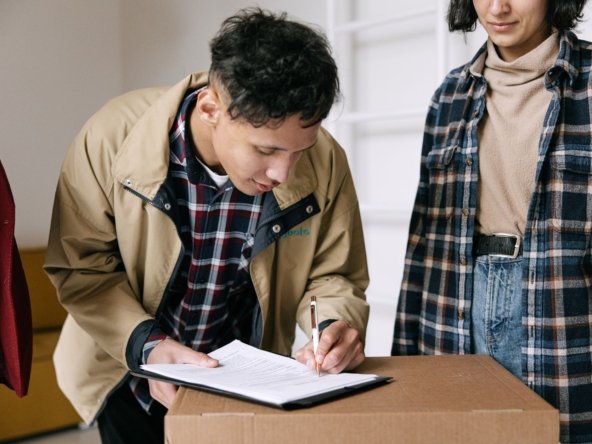 Tenant signing tenancy contract paperwork next to a moving box while relocating into a Dubai rental unit