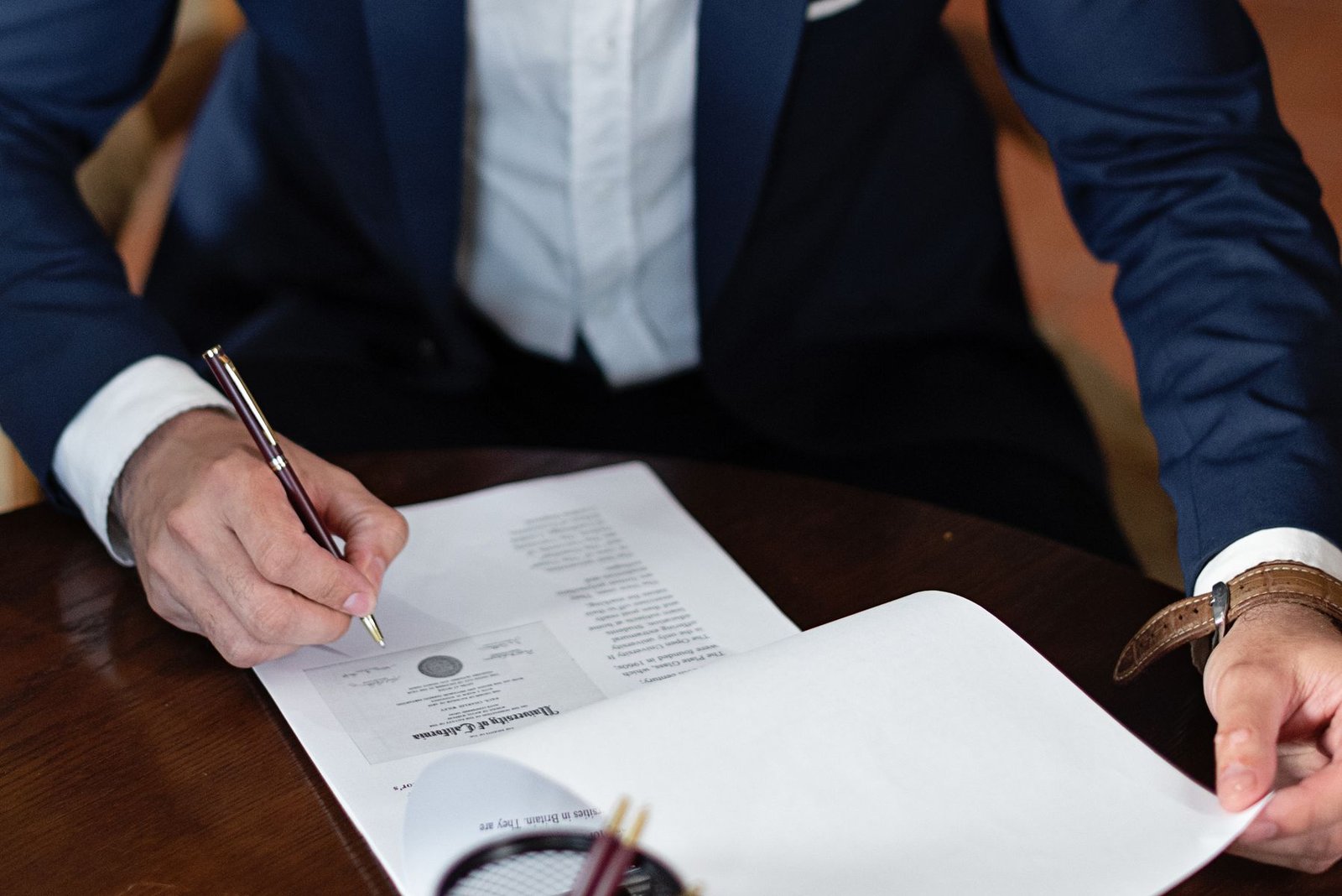 Man in a suit signing a power of attorney document at a desk
