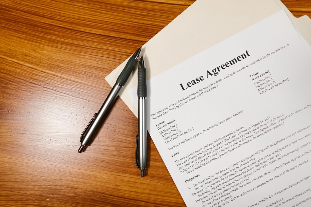Lease agreement paperwork with two pens on a wooden desk, representing Dubai rental contract terms
