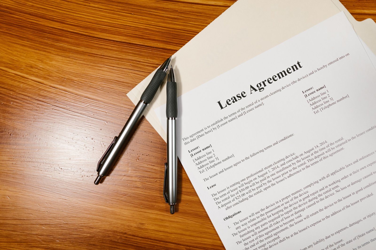 Lease agreement paperwork with two pens on a wooden desk, representing Dubai rental contract terms