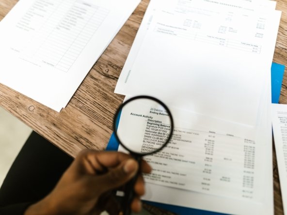 Magnifying glass held over financial documents, symbolizing verifying a Dubai property listing before paying