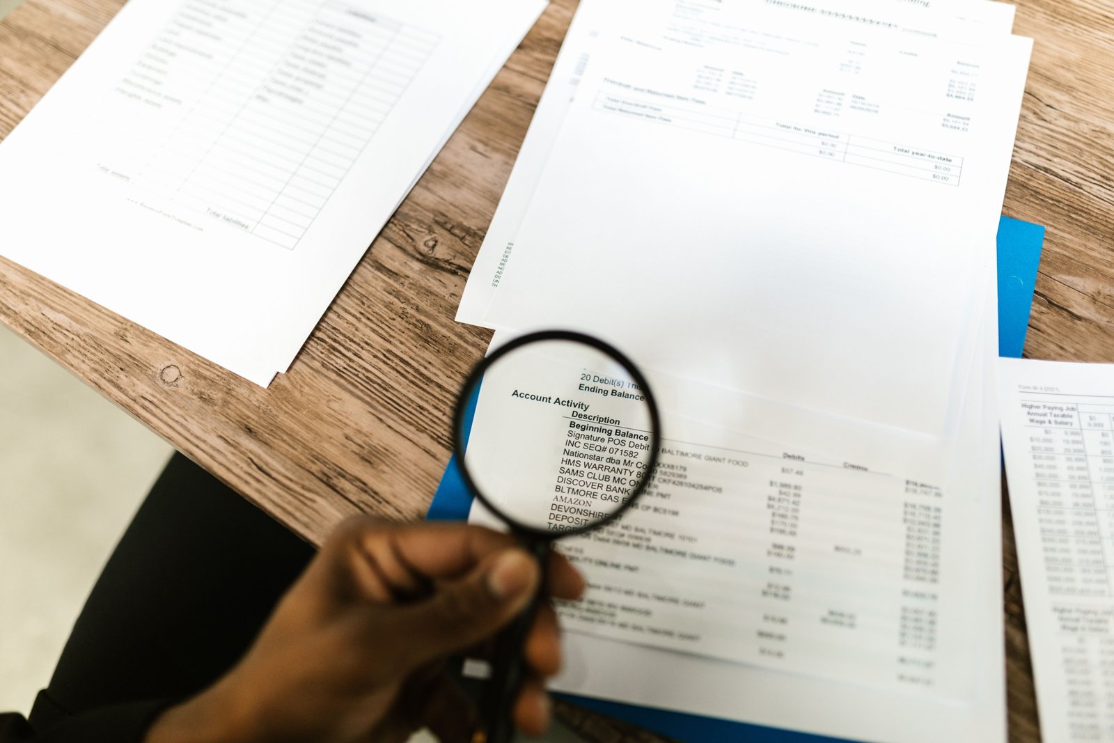 Magnifying glass held over financial documents, symbolizing verifying a Dubai property listing before paying