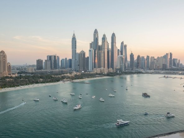 Dubai Marina skyline at sunset seen across the bay with yachts on calm water