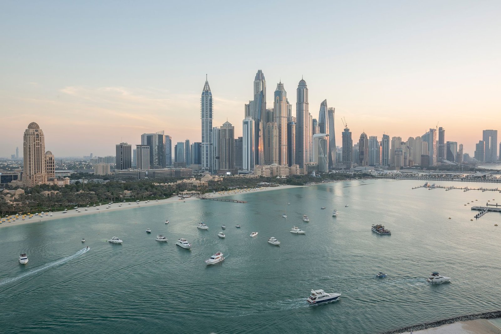 Dubai Marina skyline at sunset seen across the bay with yachts on calm water