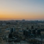 Aerial view of Dubai residential towers and low-rise districts at dawn with the Dubai Marina skyline on the horizon