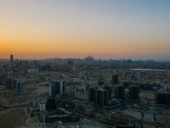 Aerial view of Dubai residential towers and low-rise districts at dawn with the Dubai Marina skyline on the horizon