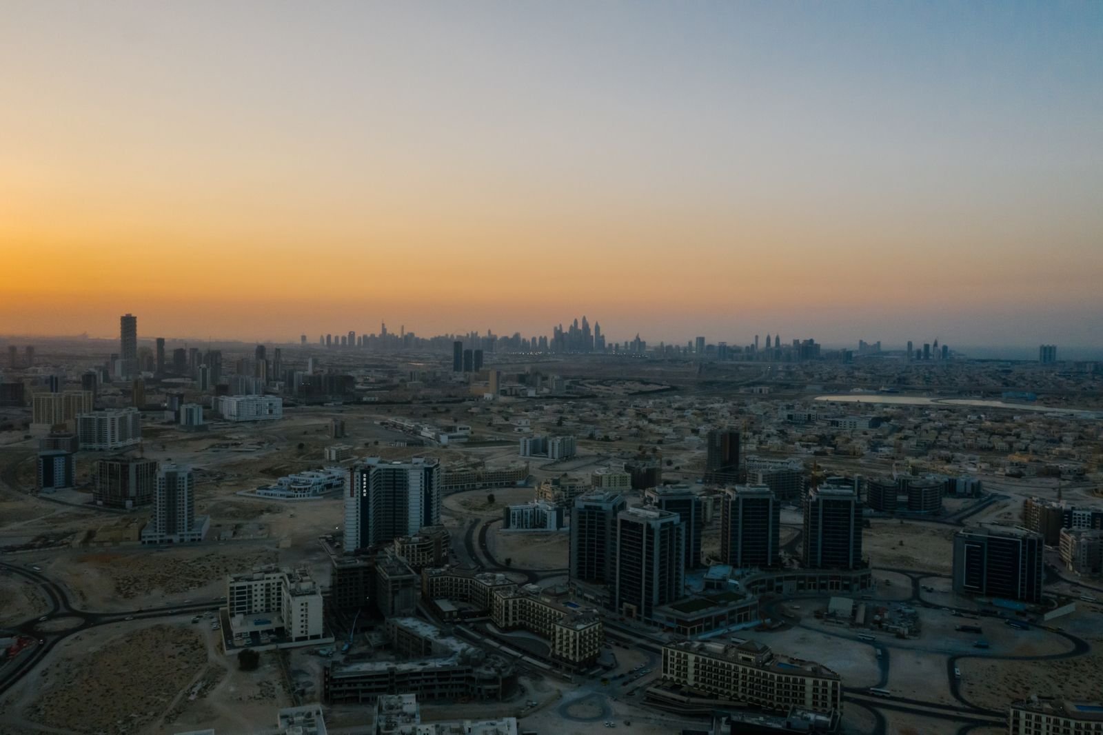 Aerial view of Dubai residential towers and low-rise districts at dawn with the Dubai Marina skyline on the horizon