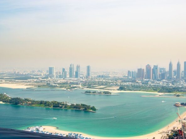 Aerial photograph of turquoise water, small islands and the Dubai skyline from above