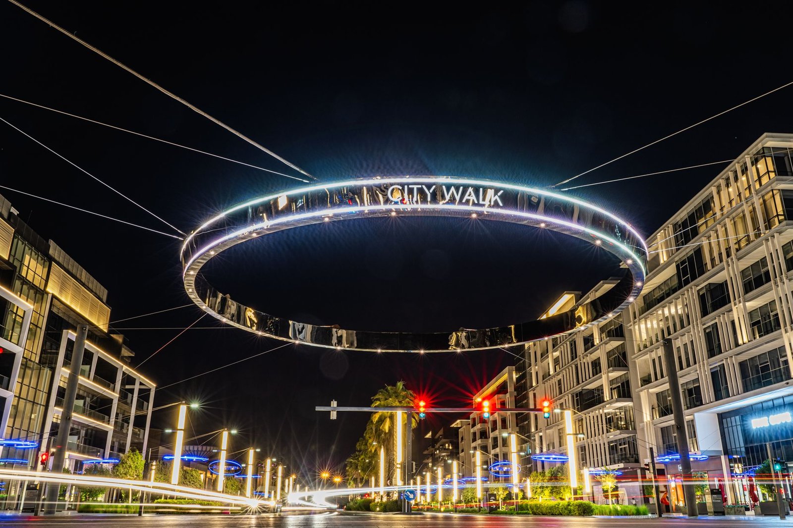 Illuminated City Walk ring sign hanging over a Dubai street at night, with low-rise residential buildings on both sides