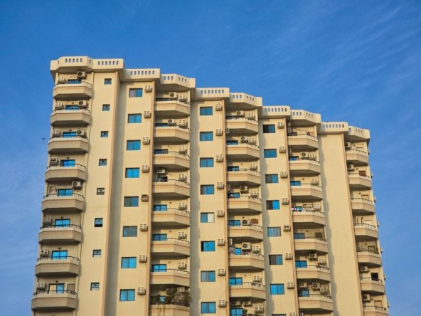 Mid-rise apartment building with balconies against a clear blue sky