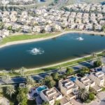 Aerial view of villas around a lake with fountains in a Dubai suburban community
