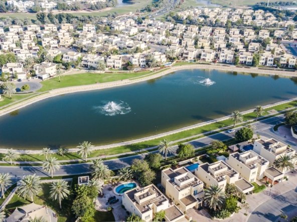 Aerial view of villas around a lake with fountains in a Dubai suburban community