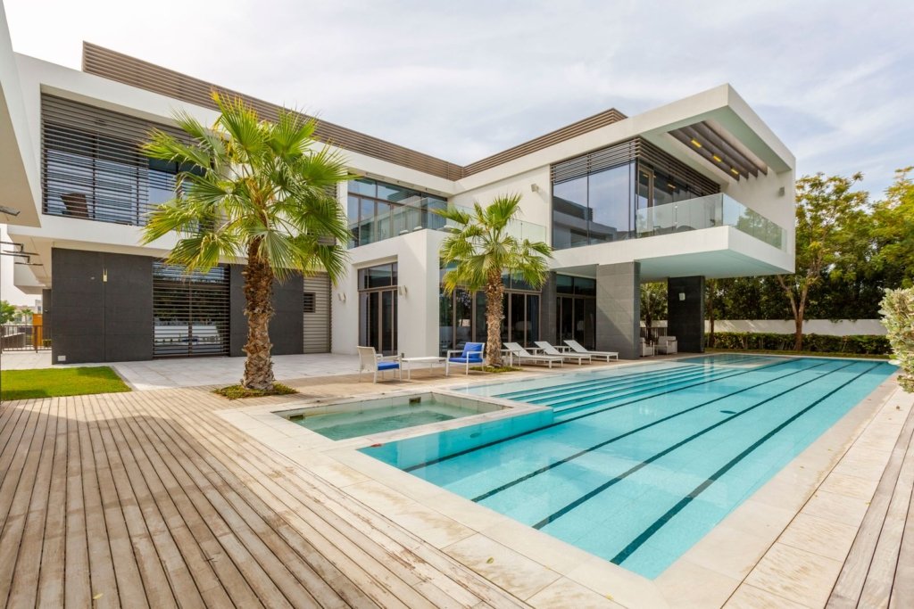 Modern luxury villa in Dubai with a long swimming pool, jacuzzi, wooden deck and palm trees