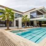 Modern luxury villa in Dubai with a long swimming pool, jacuzzi, wooden deck and palm trees