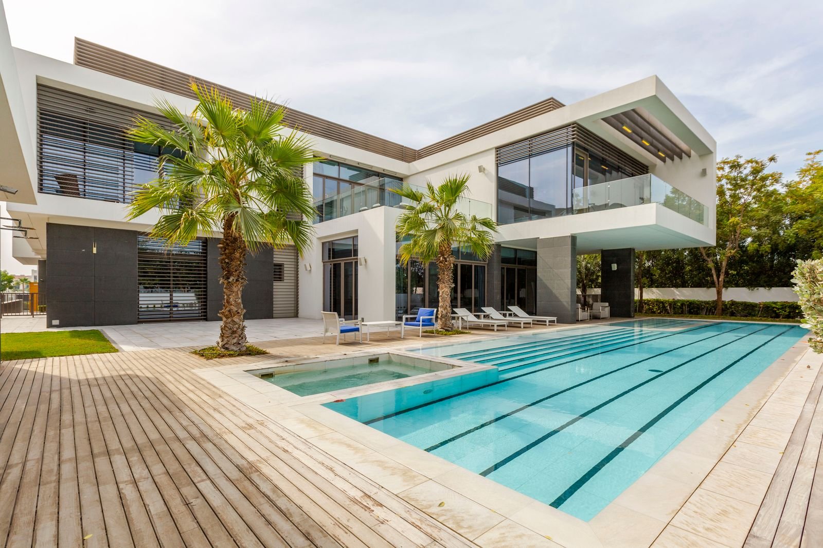 Modern luxury villa in Dubai with a long swimming pool, jacuzzi, wooden deck and palm trees
