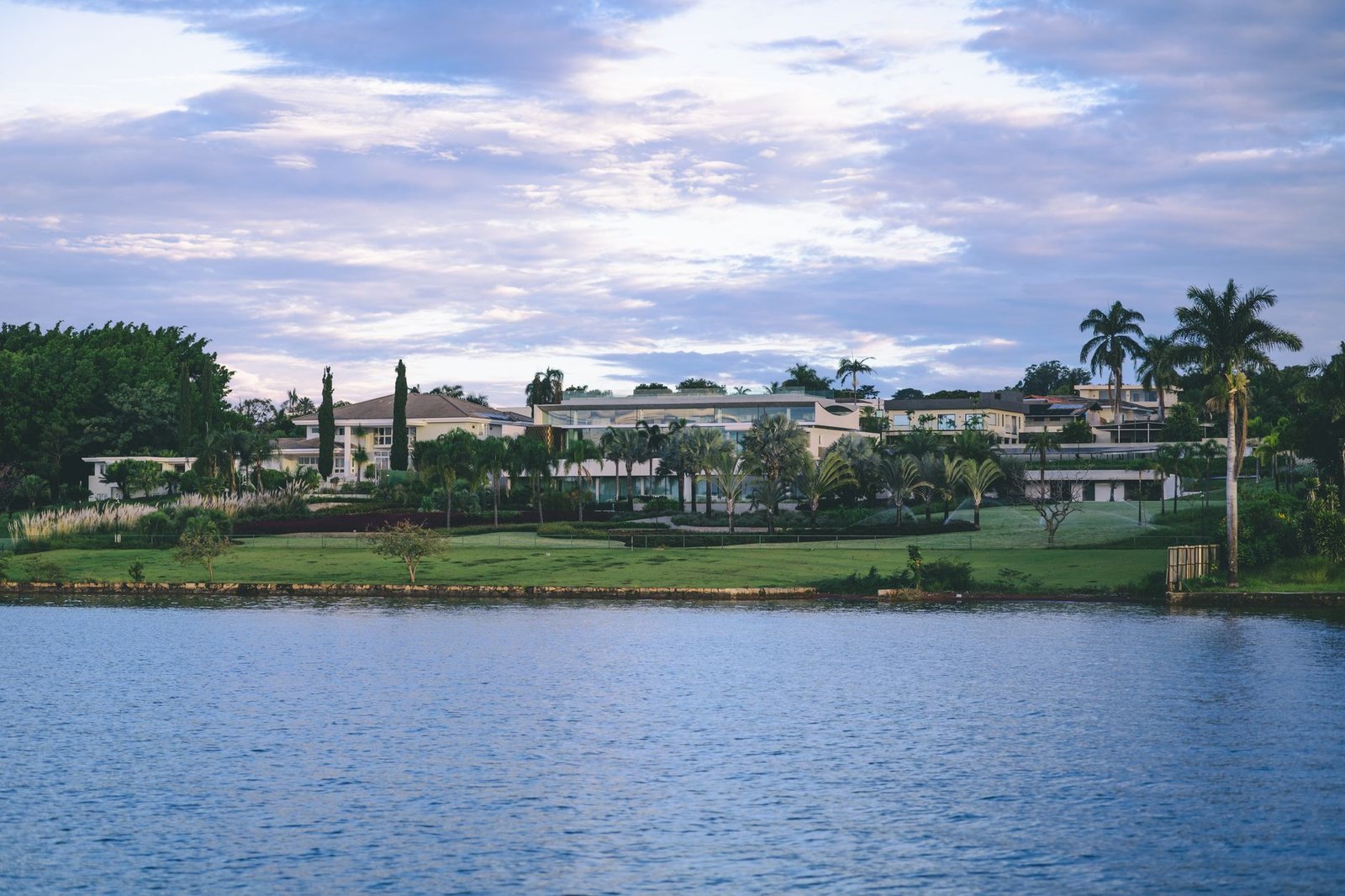 Luxury lakeside villas with landscaped gardens and palm trees beside calm water at dusk