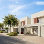 Row of modern two-storey townhouses with landscaped street under blue sky in a Dubai residential community